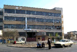 Immagine emblematica di Bucarest: palazzo quadrato, macchine mono-modello e gente per strada